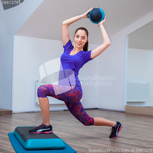 Image of Fitness girl, wearing in sneakers posing on step board with ball