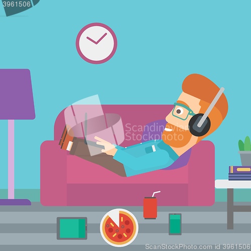 Image of Man lying on sofa with many gadgets.