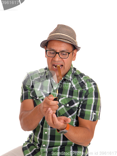 Image of Hispanic man try to light his cigar.