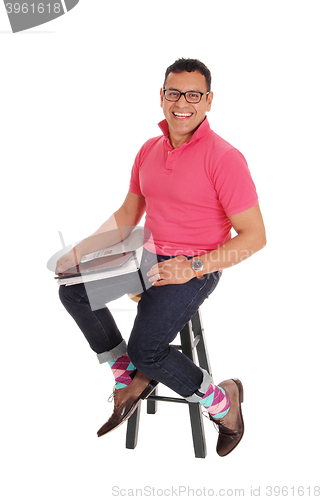 Image of Smiling Hispanic man sitting on chair. 