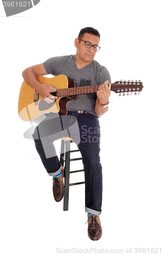 Image of Middle age man playing his guitar.