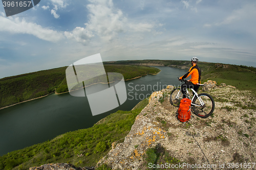 Image of Cyclist in Orange Wear Riding the Bike Down Rocky Hill