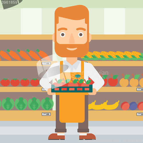 Image of Supermarket worker with box full of apples.