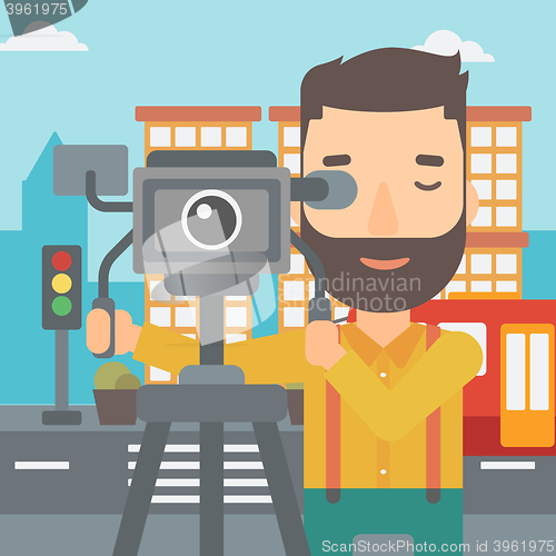 Image of Cameraman with movie camera on a tripod.