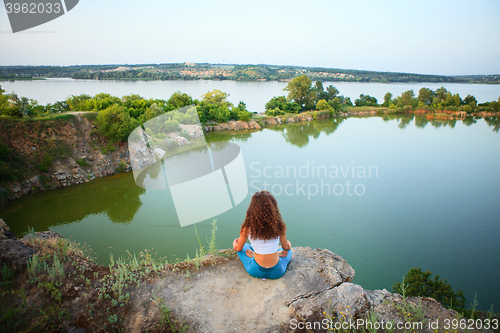 Image of Young woman is practicing yoga near river