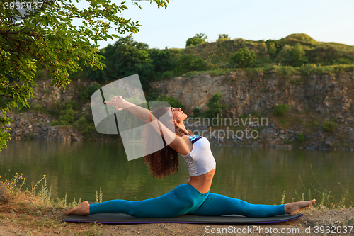 Image of Young woman is practicing yoga near river