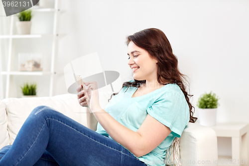 Image of happy plus size woman with smartphone at home