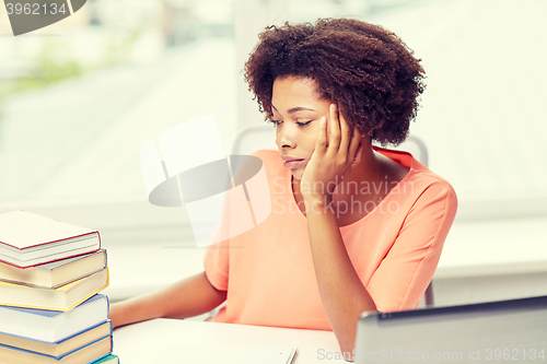 Image of bored african american woman doing homework home