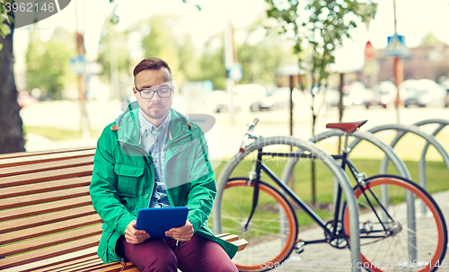 Image of sad young hipster man with tablet pc and bike