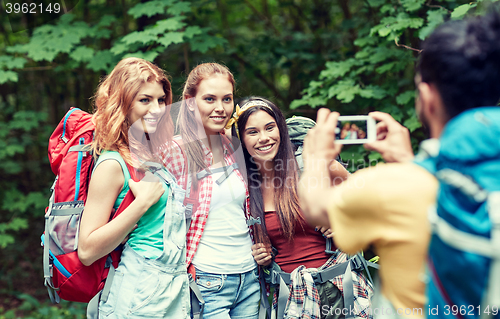 Image of friends with backpack photographing by smartphone