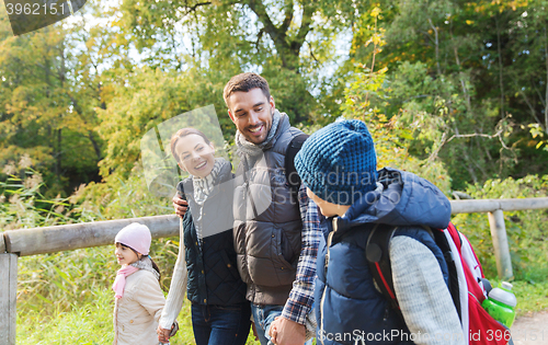 Image of happy family with backpacks hiking in woods