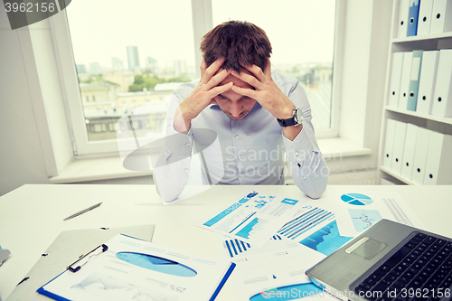 Image of stressed businessman with papers in office