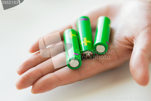 Image of close up of hand holding green alkaline batteries