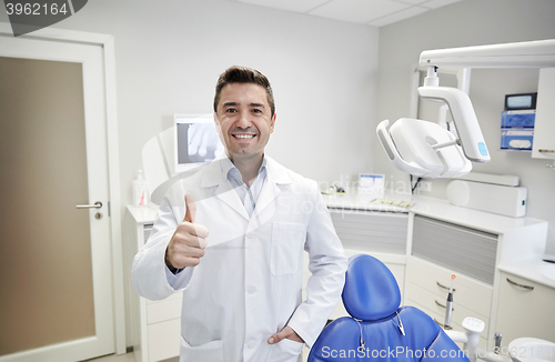 Image of happy male dentist showing thumbs up at clinic