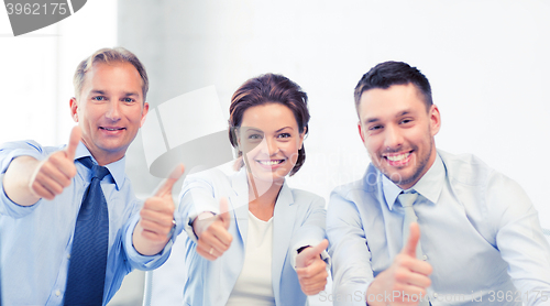 Image of business team showing thumbs up in office