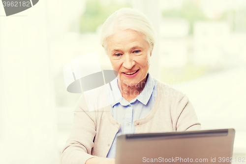 Image of happy senior woman with laptop at home