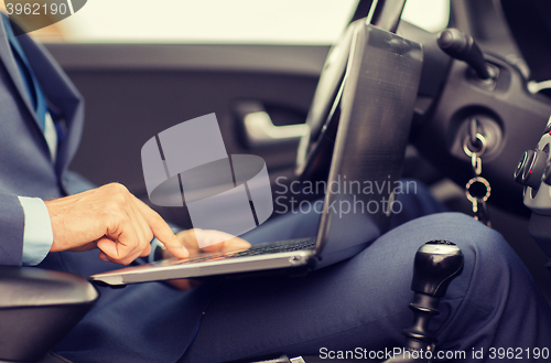 Image of close up of young man with laptop driving car