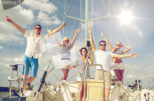 Image of smiling friends sitting on yacht deck and greeting