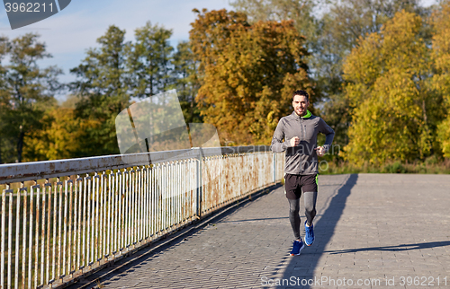 Image of happy young man running over city bridge