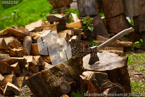 Image of Old ax on log and firewood in the background