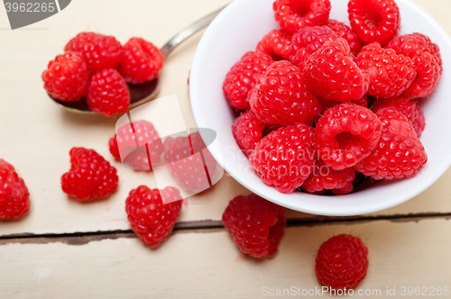 Image of bunch of fresh raspberry on a bowl and white table