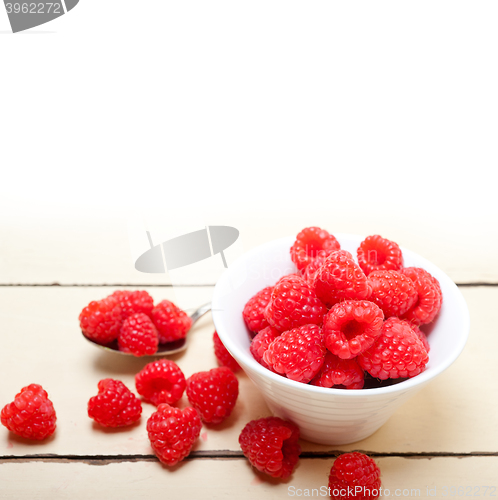 Image of bunch of fresh raspberry on a bowl and white table