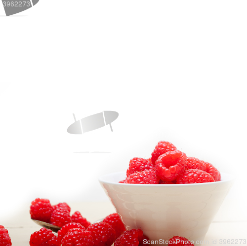 Image of bunch of fresh raspberry on a bowl and white table