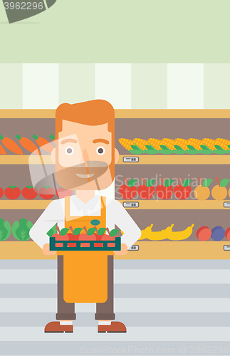 Image of Supermarket worker with box full of apples.