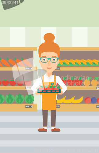 Image of Supermarket worker with box full of apples.