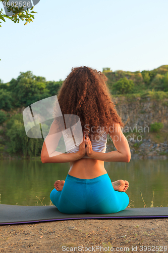 Image of Young woman is practicing yoga near river