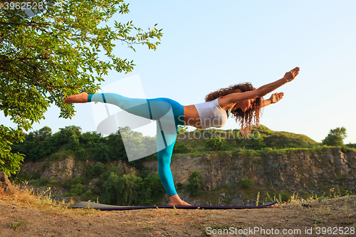 Image of Young woman is practicing yoga near river