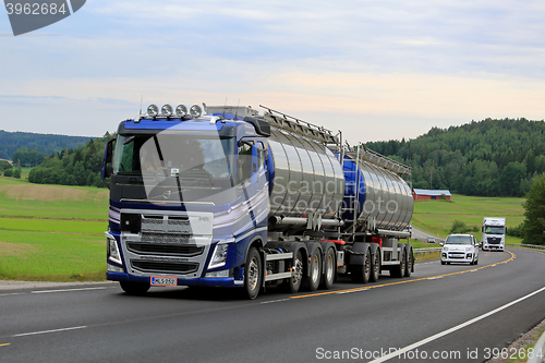 Image of New Blue Volvo Tank Truck on Scenic Road at Summer