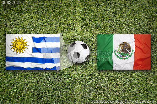 Image of Uruguay vs. Mexico flags on soccer field