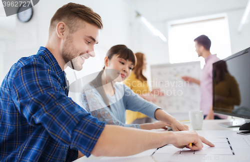 Image of creative team with blueprint at office