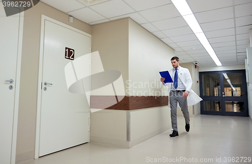 Image of doctor with clipboard walking along hospital