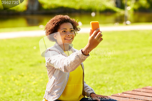 Image of happy african woman taking selfie with smartphone