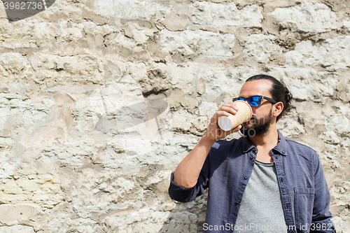 Image of man drinking coffee from paper cup on street