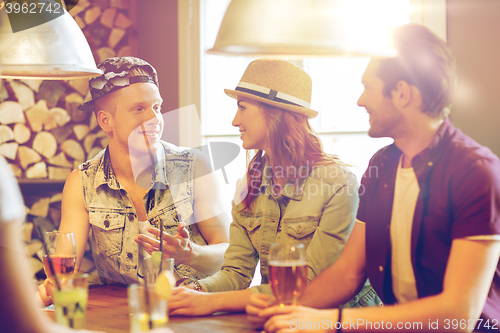 Image of happy friends drinking beer and cocktails at bar