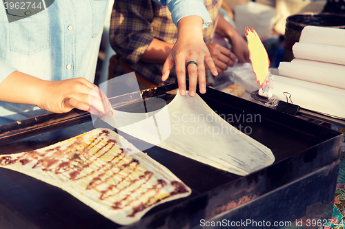 Image of close up of cook frying pancakes at street market