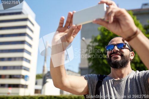 Image of man taking video or selfie by smartphone in city