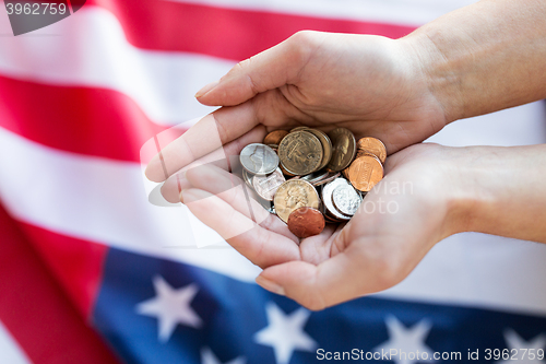 Image of close up of hands with coins over american flag