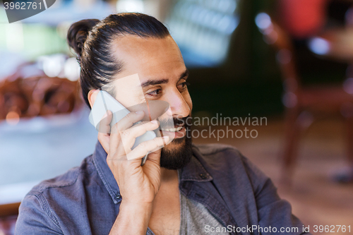 Image of happy man calling on smartphone at bar or pub