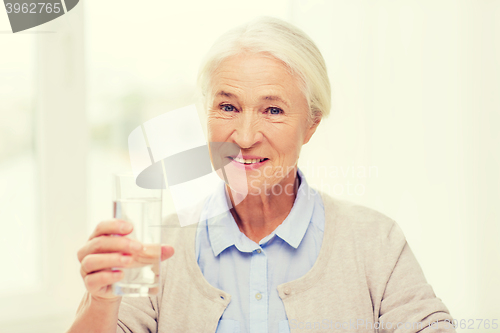 Image of happy senior woman with glass of water at home