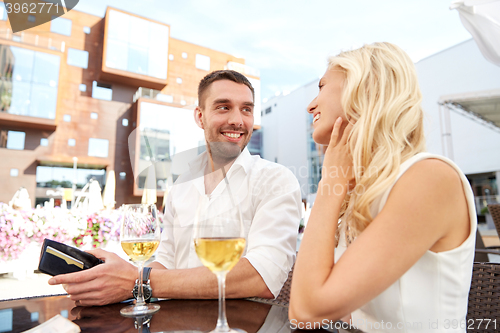 Image of happy couple with wallet paying bill at restaurant