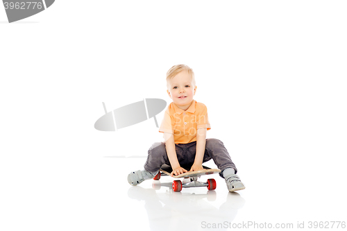 Image of happy little boy sitting on skateboard