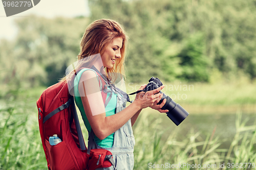 Image of happy woman with backpack and camera outdoors