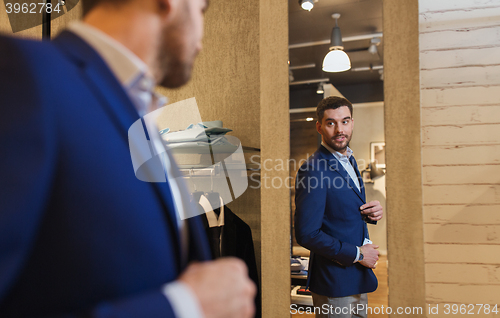 Image of man trying jacket on at mirror in clothing store