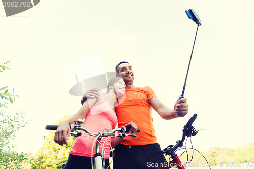 Image of couple with bicycle and smartphone selfie stick