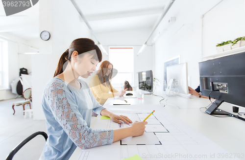 Image of architect woman drawing on blueprint at office