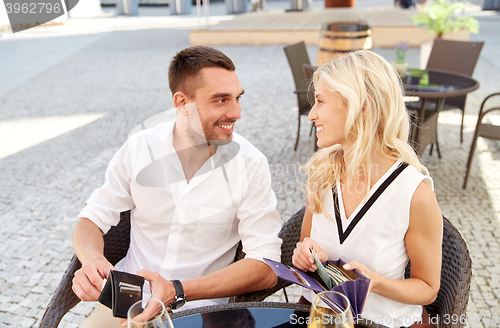 Image of happy couple with wallet paying bill at restaurant